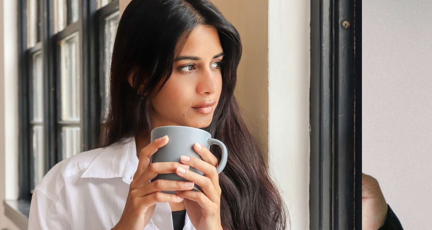 Young woman holding coffee cup thinking about all the things you can sell on ebay now that she knows how to make money on ebay