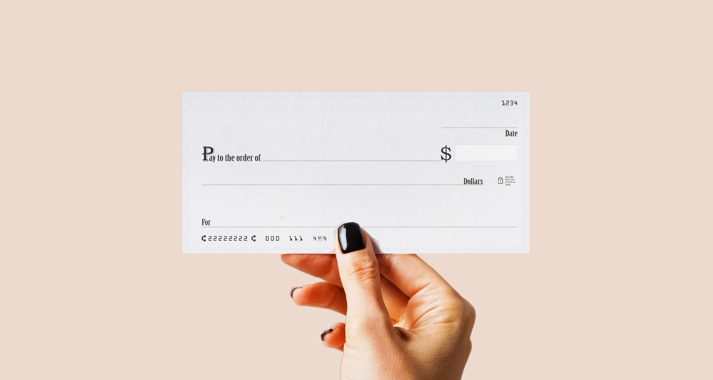a hand holding a cheque showing How to Write a Check
