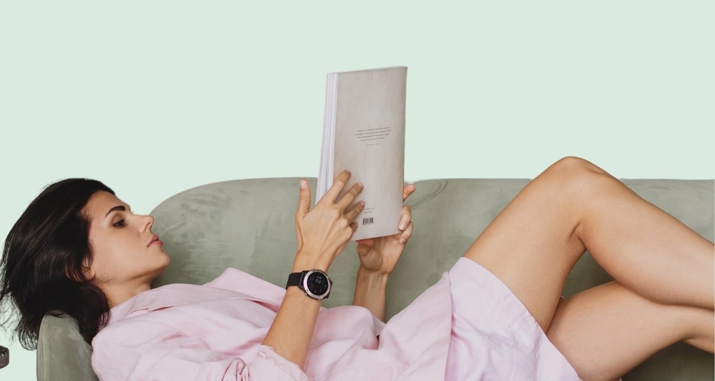 Business woman reclines on couch and reads about Rich Vs. Wealthy: 8 Main Differences