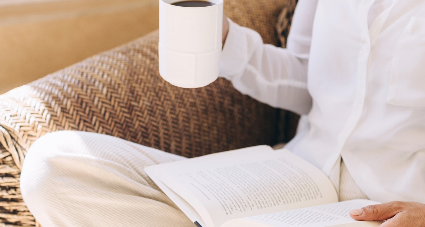 woman reading a book while holding a coffee enjoying knowing Simple Ways to Get Free Books by Mail