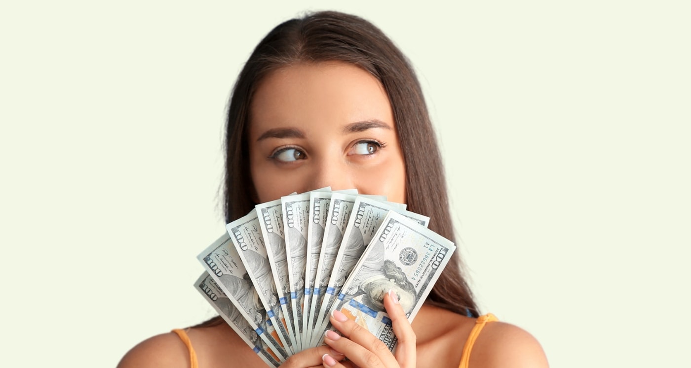woman covers face with cash and asks What Does Your Money Personality Mean for Your Finances?