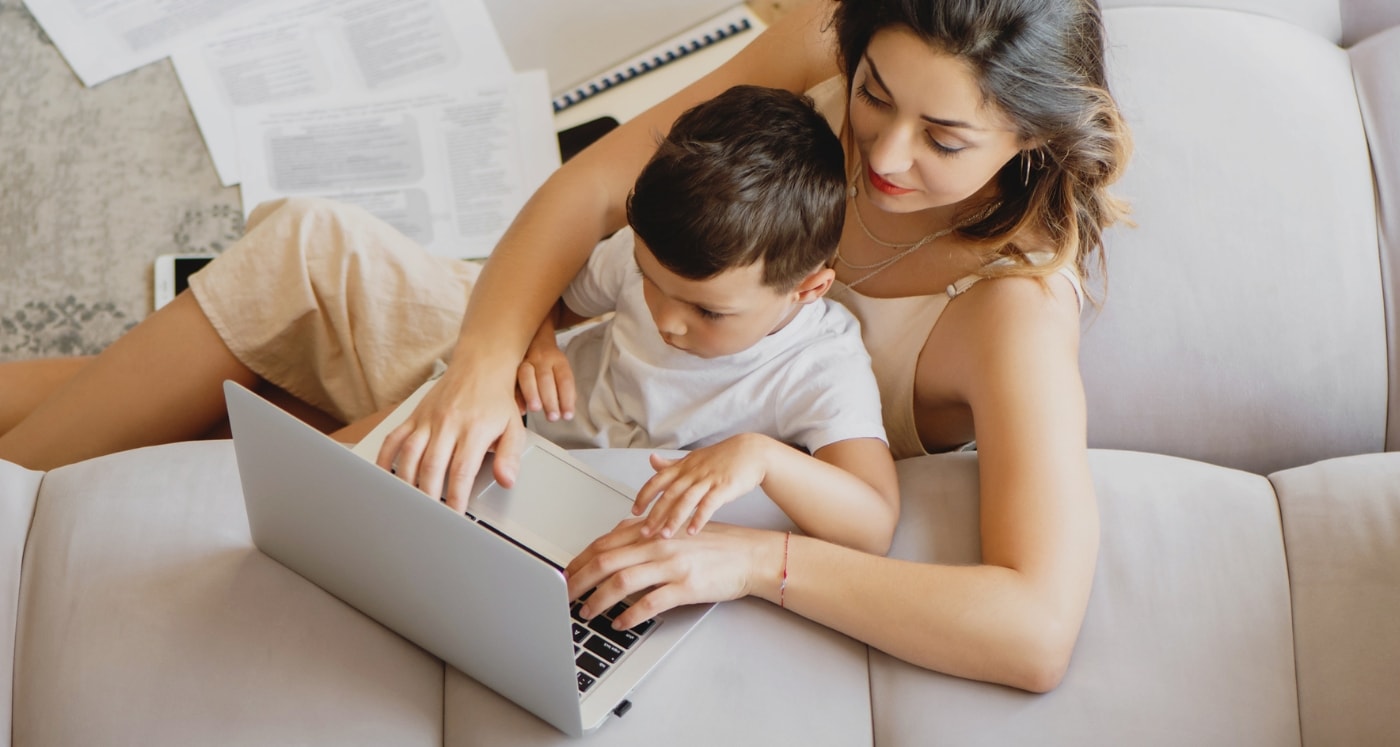 mom holding child while she works from home, studying the list of th Best Legitimate Stay At Home Jobs For Moms That Pay Great