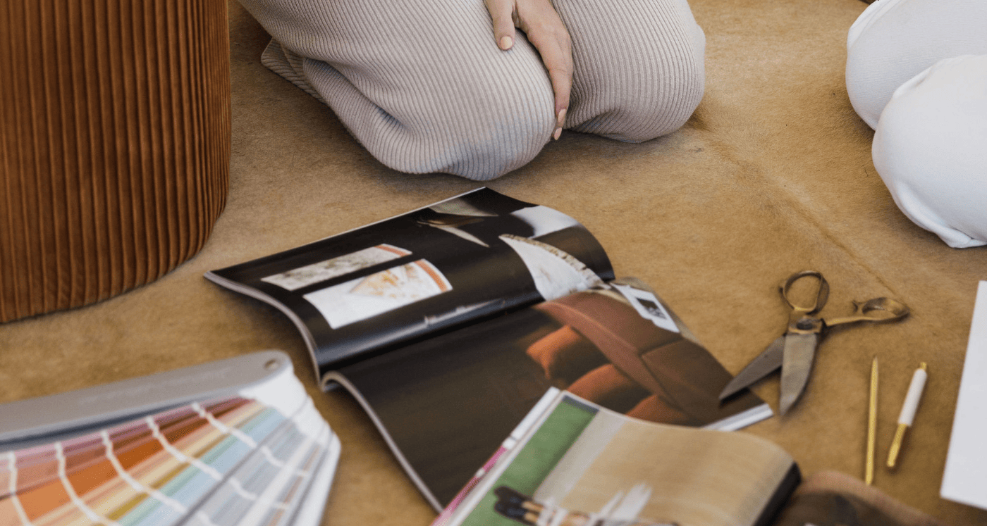 woman sitting on floor cutting images out of a magazine and using other Creative Visual Ways To Pay Off Debt