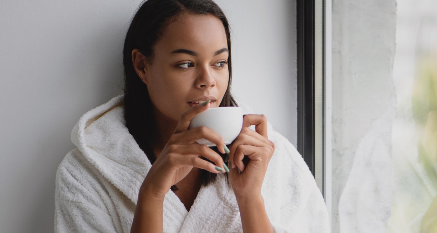 A woman sips her coffee as she considers the Positive Reasons To Become A Cheapskate