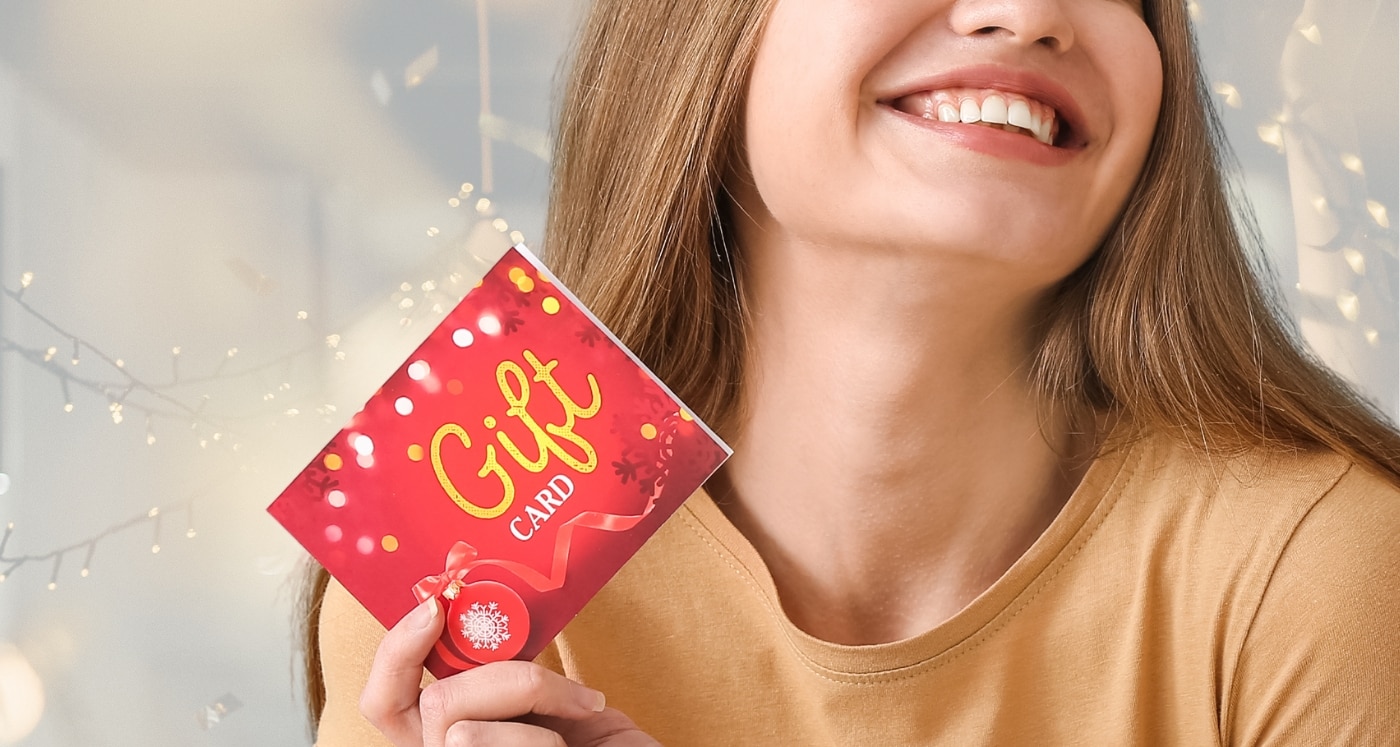 Smiling woman holding gift card after learning How To Convert Visa Gift Cards To Cash
