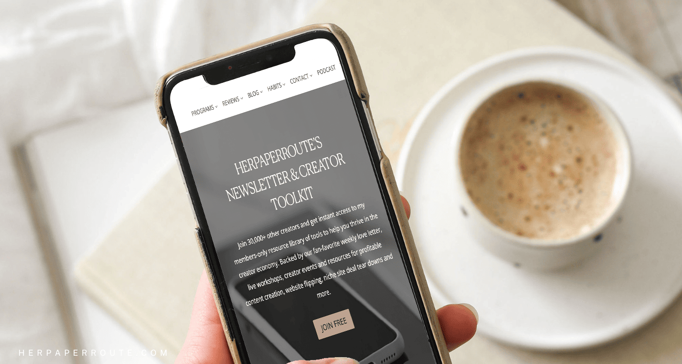 Holding phone showing HerPaperRoute newsletter - How To Know If Your Newsletter Strategy Is Working