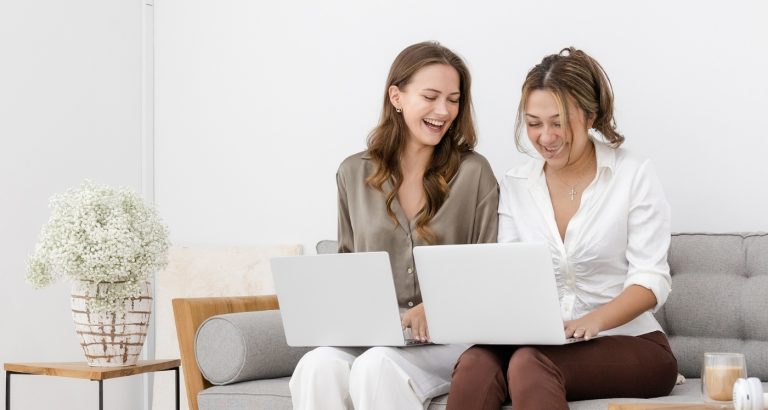 two business owners smile at their laptop computers using one of the 11 Best Landing Page Builders reviews at HerPaperRoute