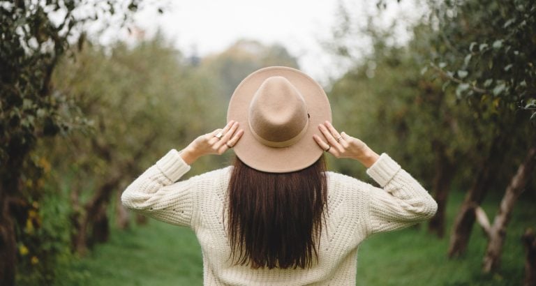 woman wears hat as she walks outside on September morning learning about September Content Ideas - What To Post This Month