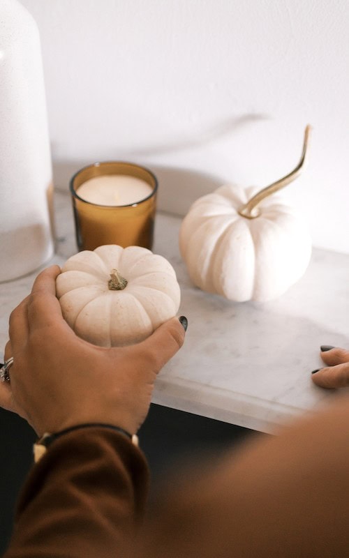 Woman sets up halloween mantle with pumpkins, Offer Holiday decoration setup services this Fall