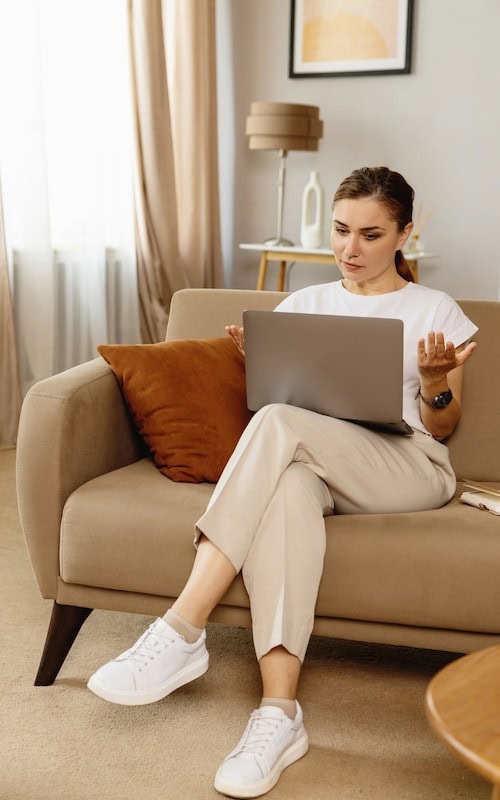 Young woman sits on couch and earns money selling courses in the Winter