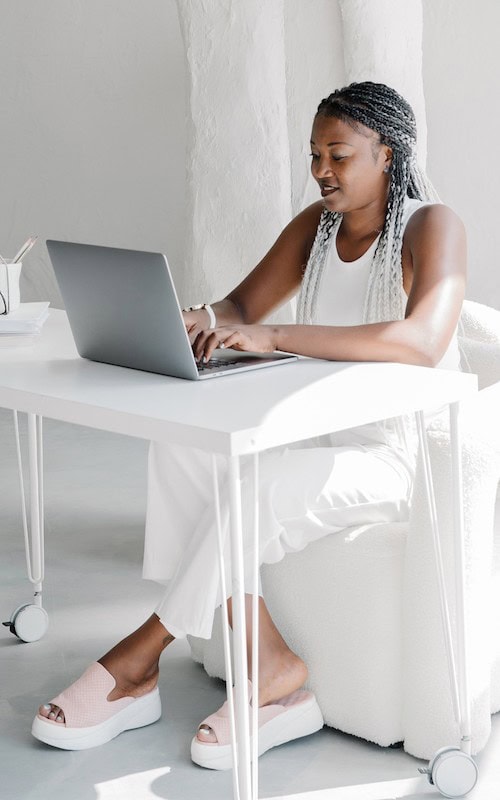 woman sites at desk in home office running a personal shopping winter side hustle for the holidays