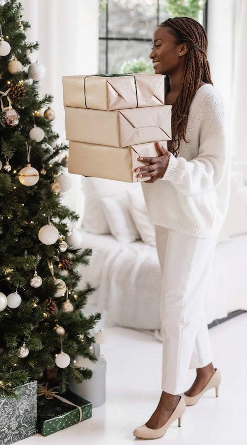 woman carries presents to tree winter content ideas list for what to post on her blog and socials in december