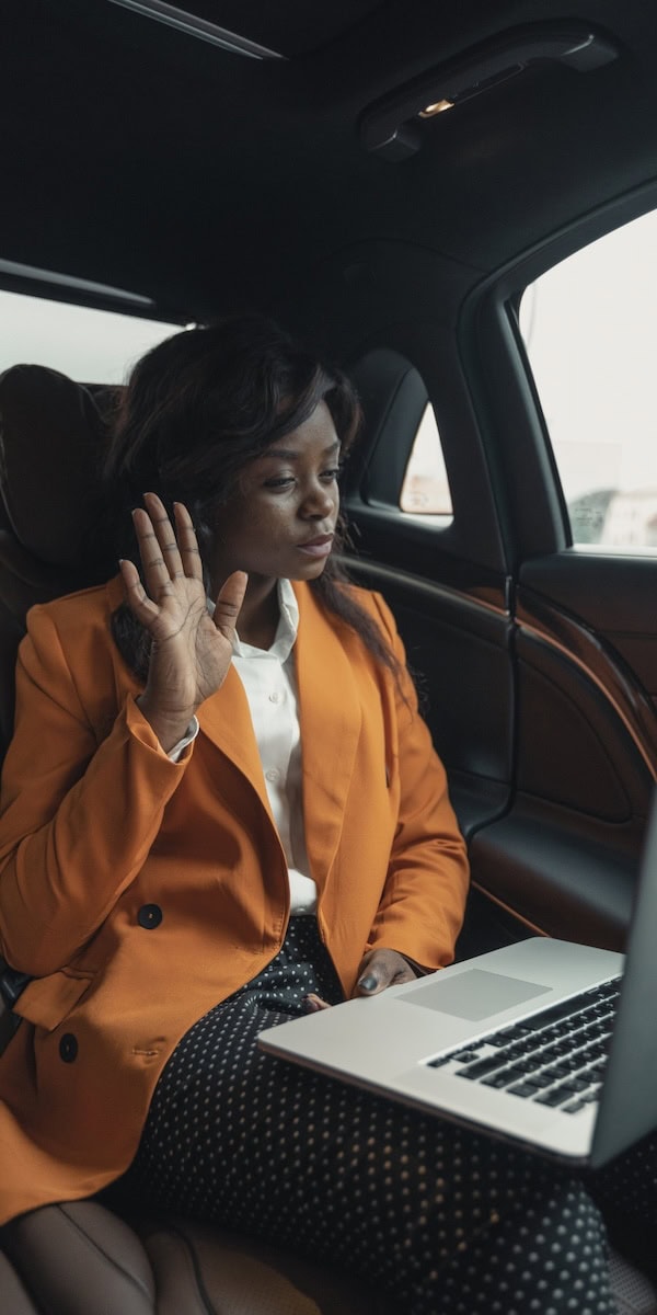 business woman works on her laptop in backseat of Uber now that she can select female-only Uber drivers step by step