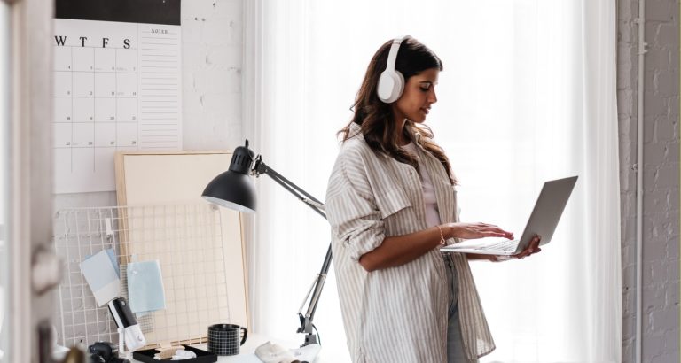 woman with headphones listening to HerPaperRoute podcast to learn what to do after buying a website